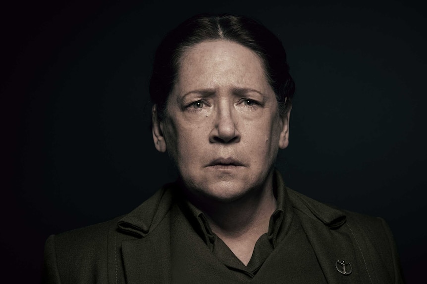 Ann Dowd, in character as Aunt Lydia, stares forlornly