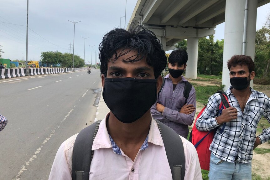 A young man in a face mask walking down the side of a freeway
