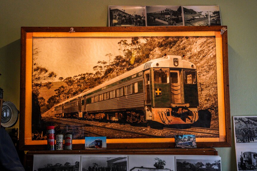 A framed black and white photograph of a train on tracks hangs in a dimly lit room.