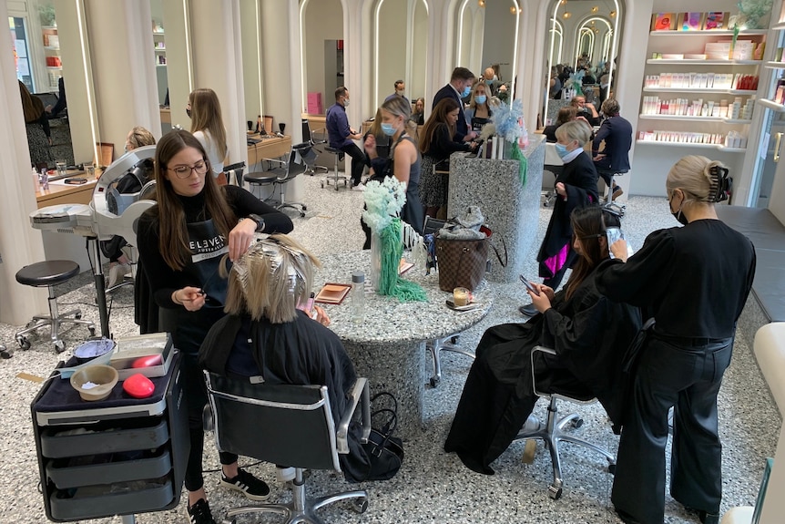 A hairdressing salon with several customers in it.