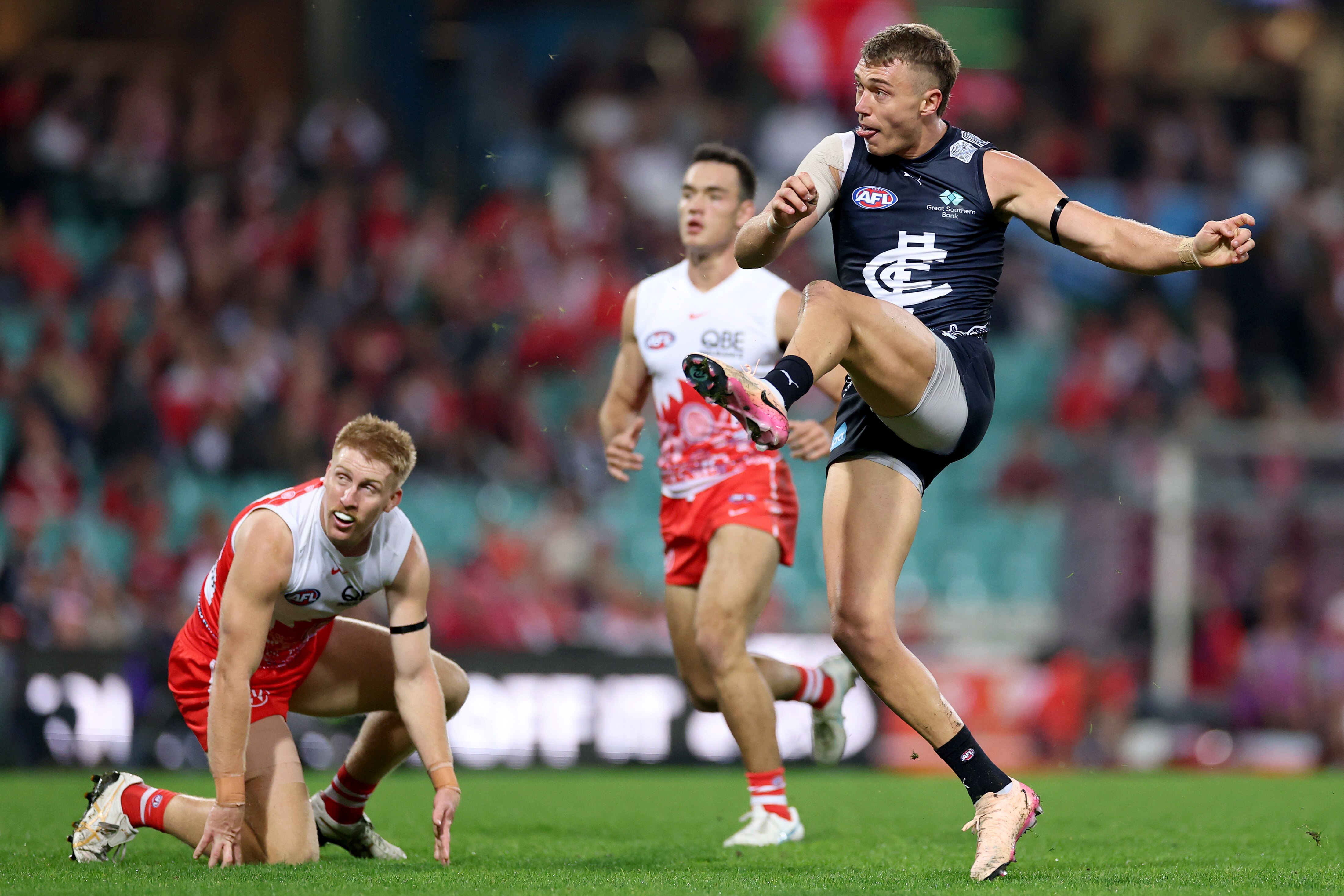 Patrick Cripps kicks the ball while Swans defenders watch on