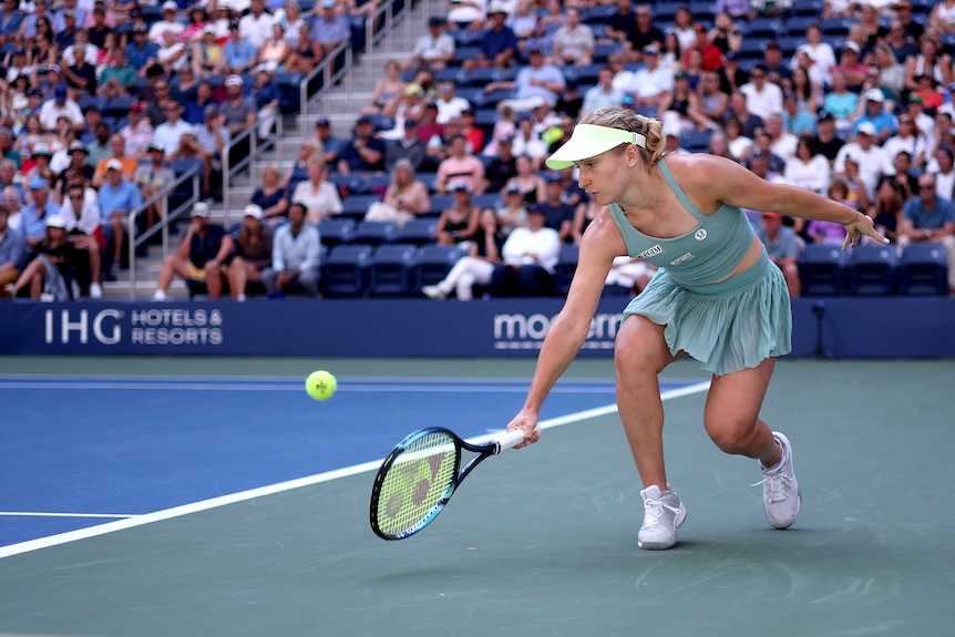 Daria Saville plays a running one-handed backhand during a US Open tennis match against Iga Swiatek.