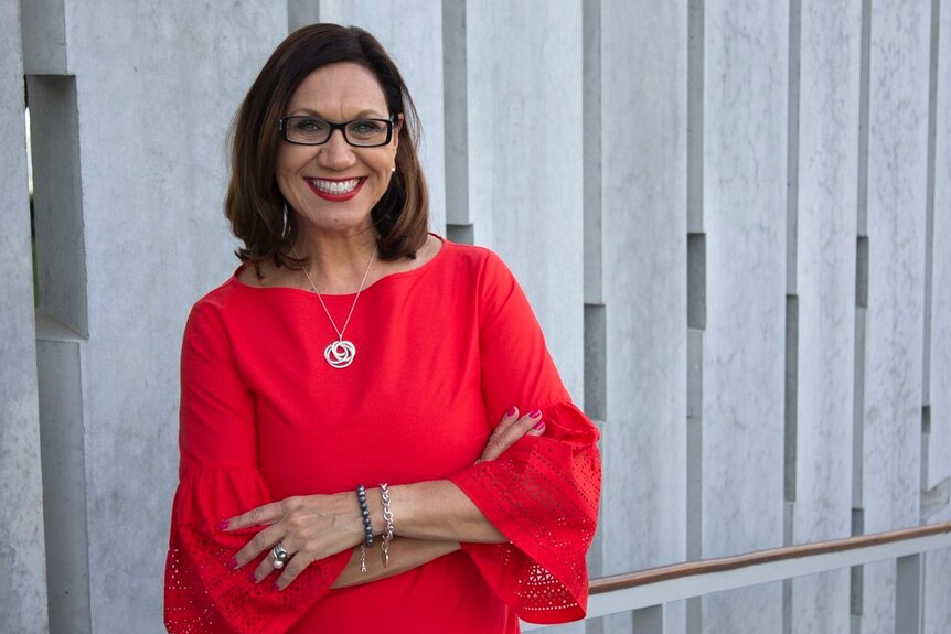 Lady dressed in red dress with arms crossed.