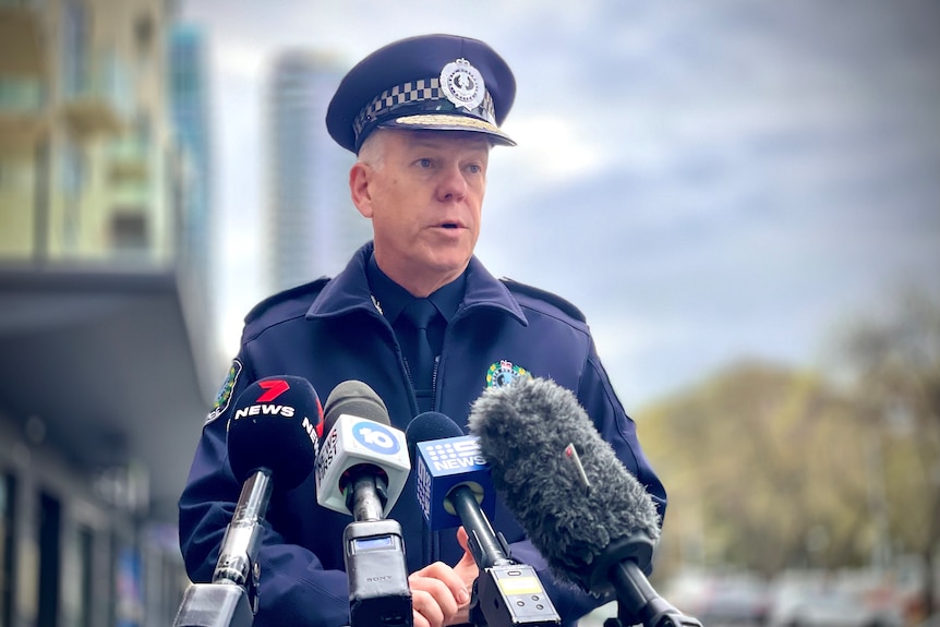 A male police officer wearing a peaked hat with a magpie logo on it