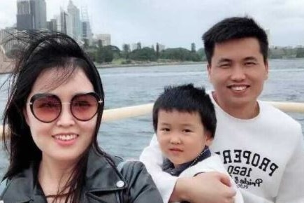 A young Chinese family smiling for a photo on Sydney Harbour.