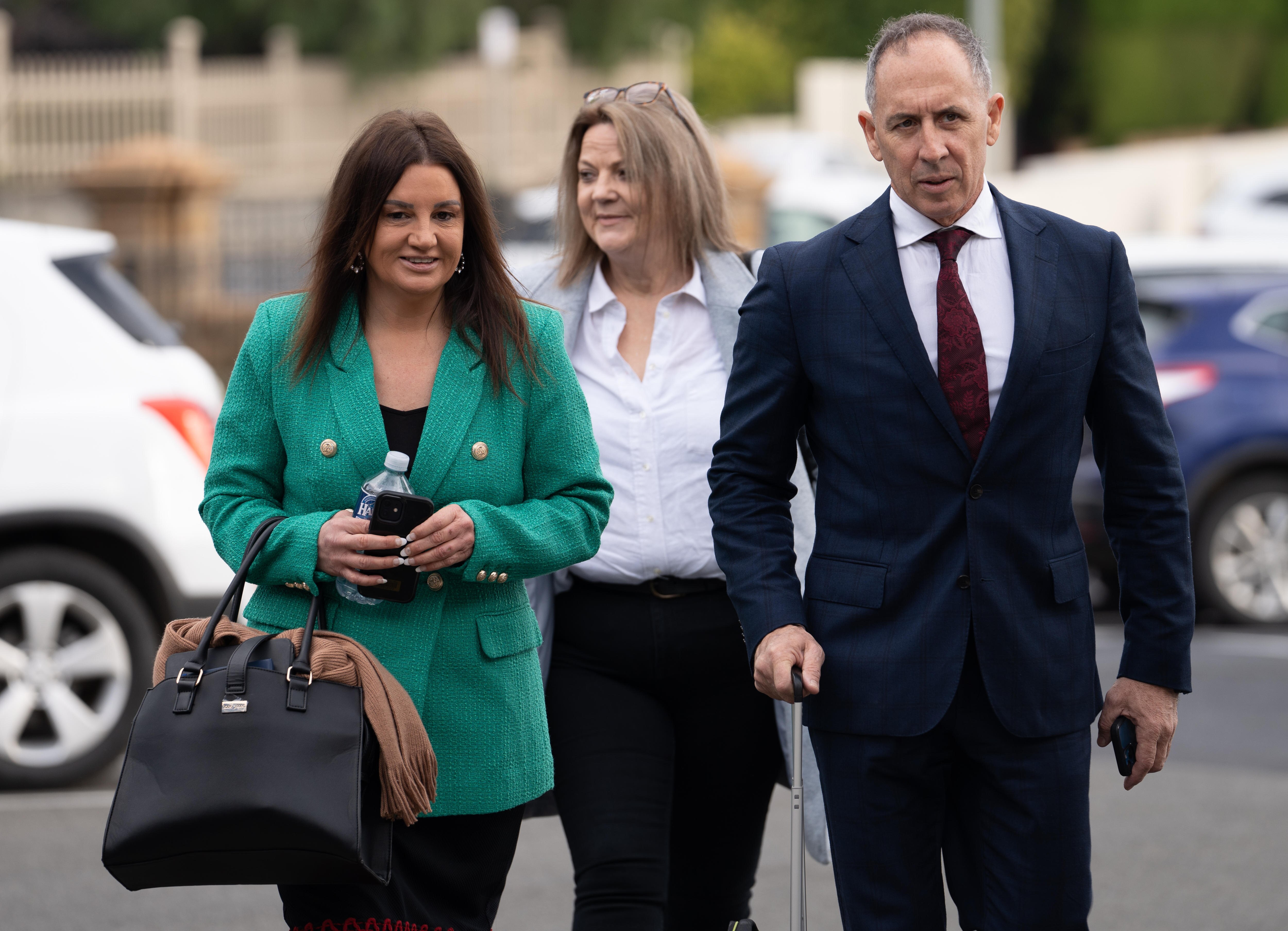 Jacqui Lambie smiles and speaks with a man and she walks down a path.