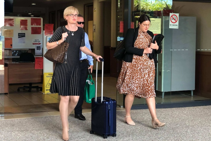 Deborah Holliday QC wheeling suitcase, a man behind her and woman next to her all walking out of the court building.