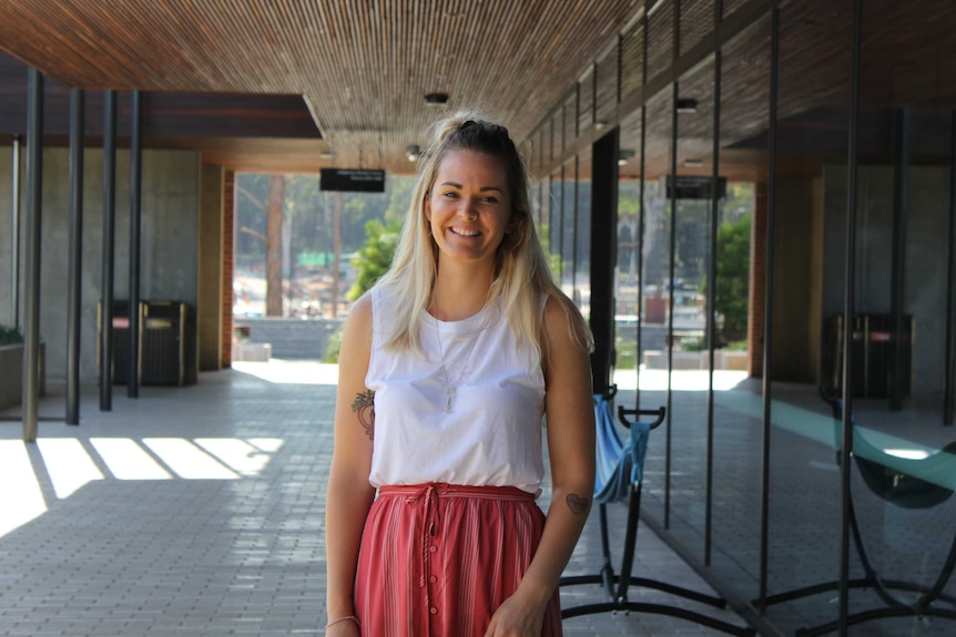 Image of blond haired student standing in University corridor.