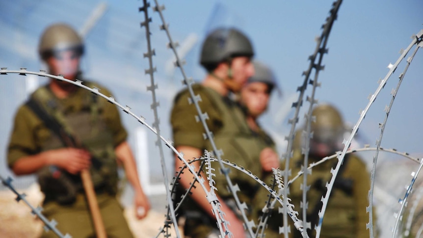 Israeli soldiers in front of razor wire.