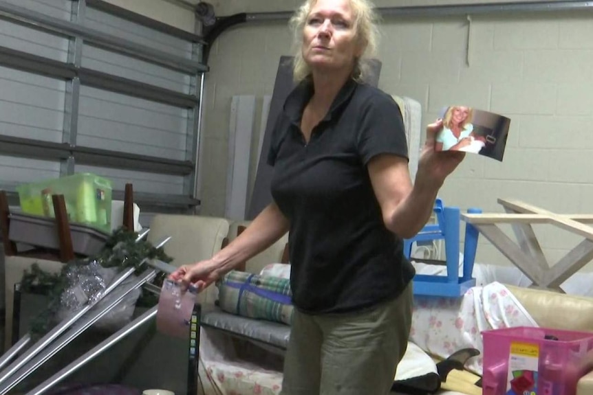 woman holding up a photo in a garage covered in water