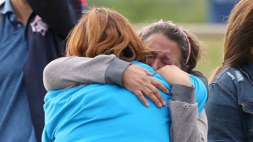 One woman embraces another while crying.