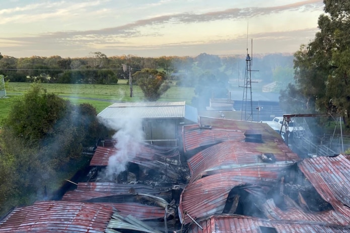 Smoke rises from a series of crumpled red roofs. 