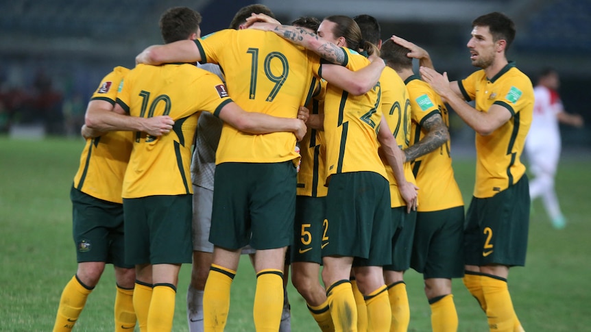 The whole Socceroos team joins arm-in-arm together