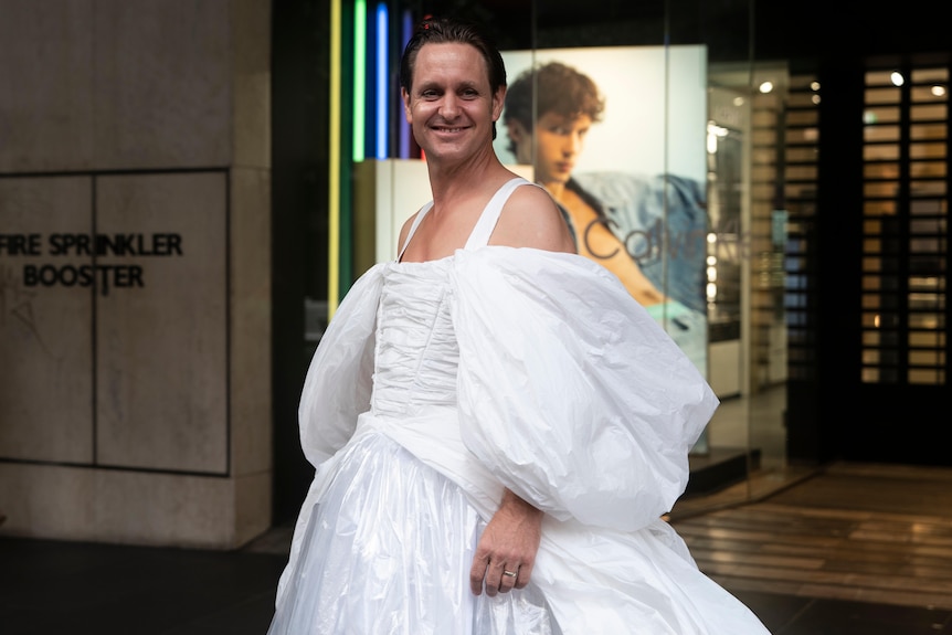 Craig Reucassel wearing an old wedding dress on a city street in Sydney