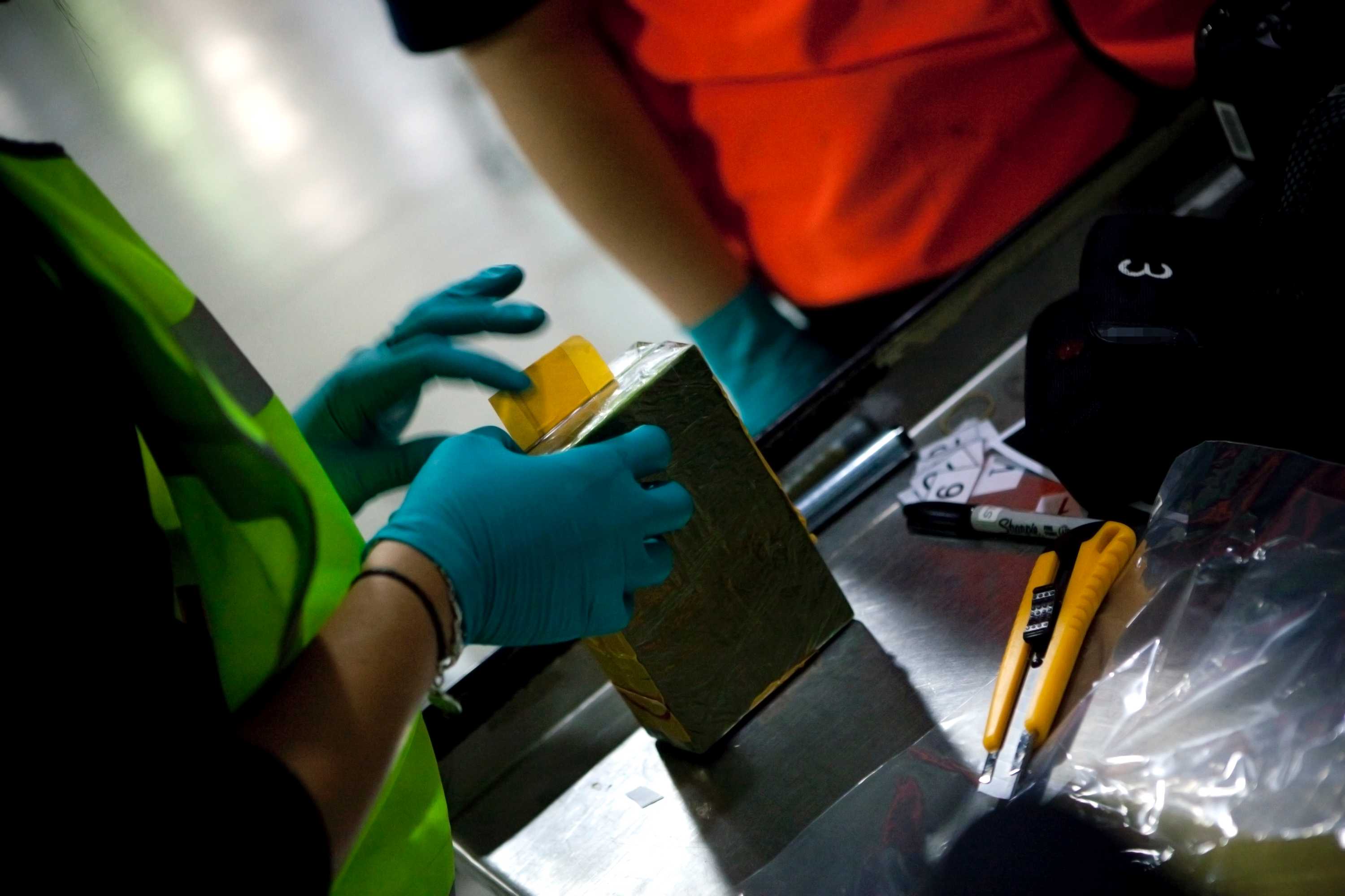 Customs officers examine a package of heroin.