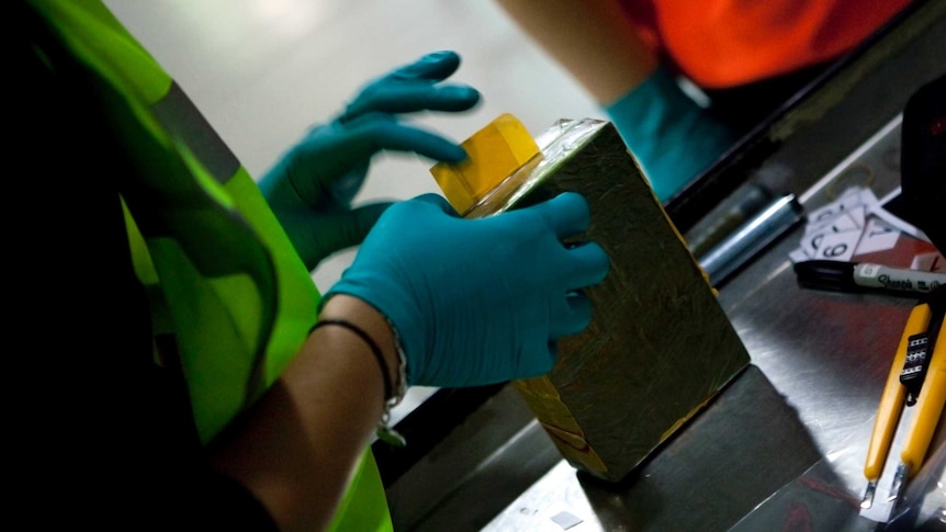 Customs officers examine a package of heroin.