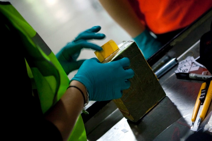 Customs officers examine a package of heroin.