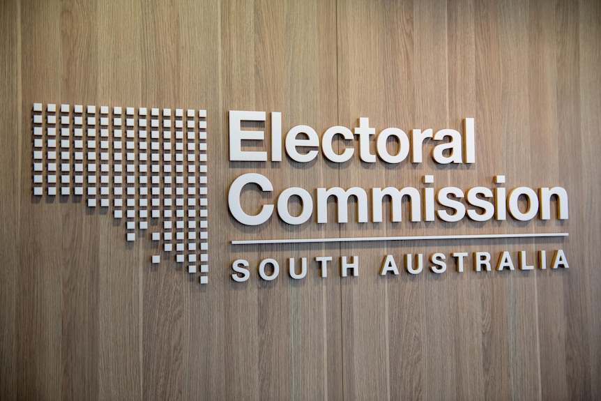 The logo of the Electoral Commission of South Australia on a brown wall