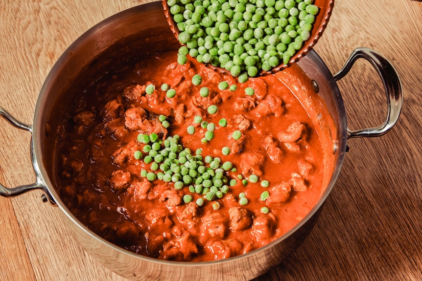 Fry pan of sausage and tomato pasta sauce, frozen peas being thrown in, a weeknight pasta.