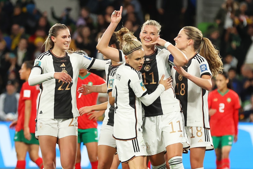 A German striker makes a phone call gesture with her hand as she receives congratulations for a goal.