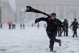 A young priest throws a snowball during a heavy snowfall in Saint Peter's Square.