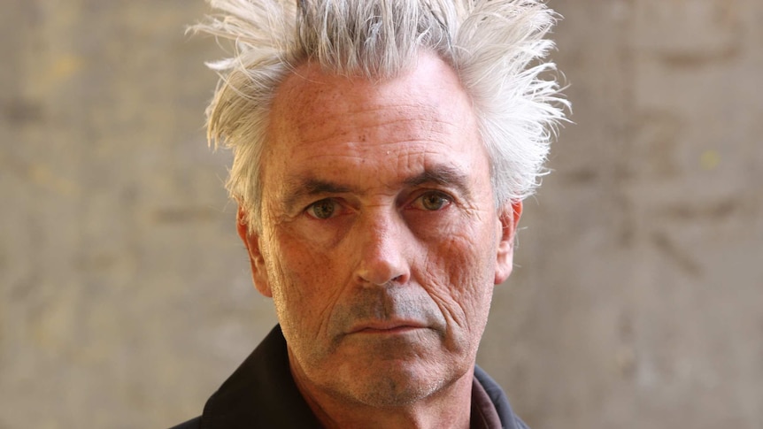 singer songwriter stephen cummings has spiky grey hair and is looking into the camera