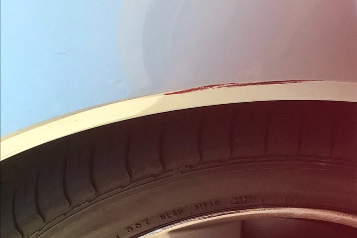 The damage to Annette's car: a scratch on the white paint above a wheel.