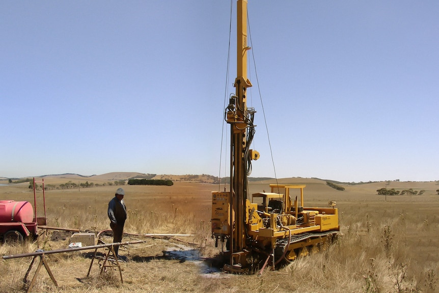 A worker observes a drill going into the land.
