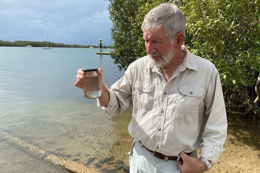Ian Bell holds a jar with water from the Caboolture River.