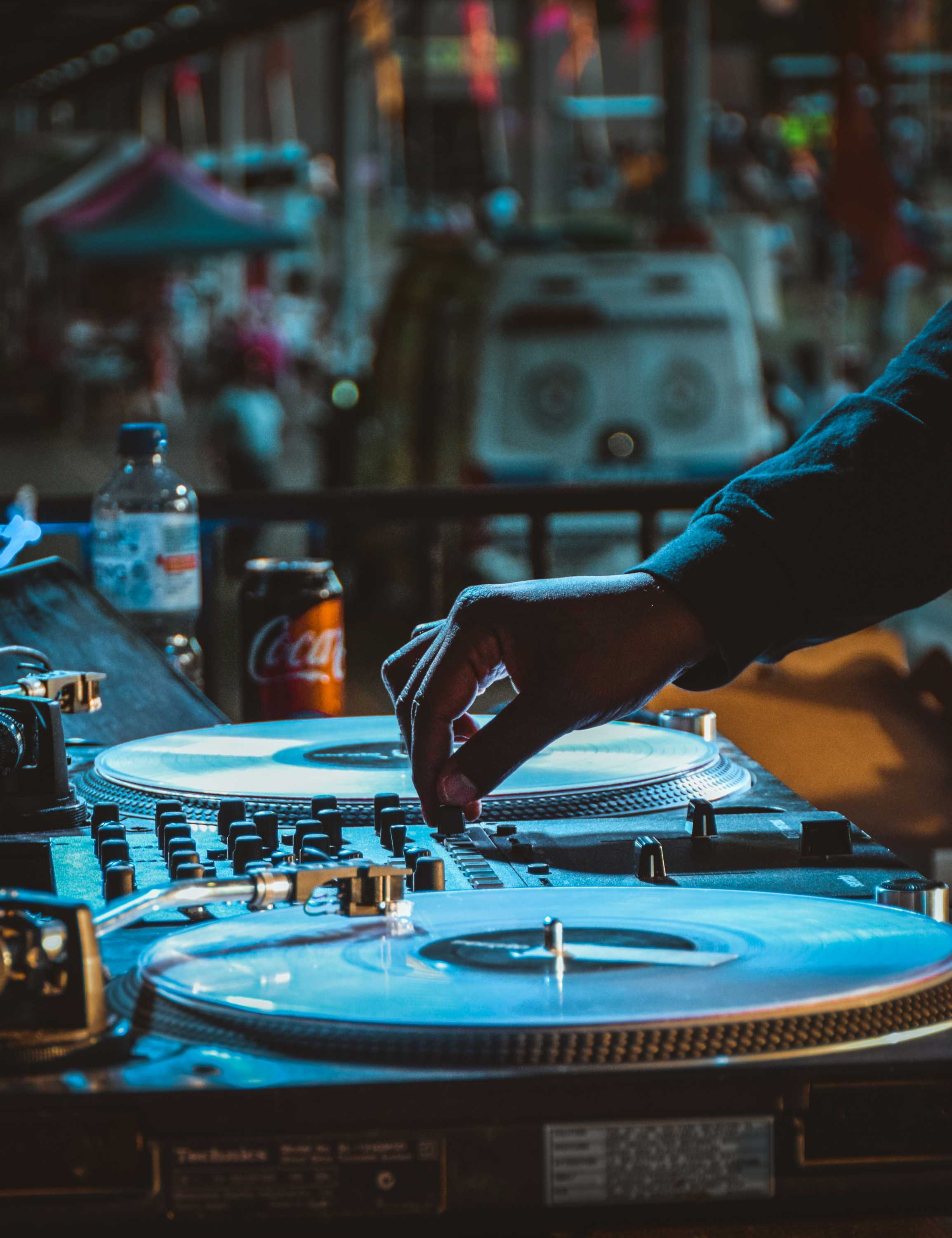 A DJ performing with two turntables in a dimly lit space.