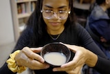 A young woman holds a bowl of kava. 