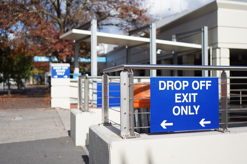 A blue sign reads 'drop off exit only' with two white arrows pointing to the left.