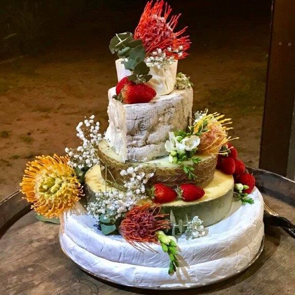five layers of cheese stacked on top of each other to look like a cake with flowers and fruit placed on top of it.