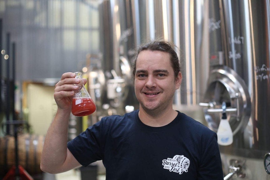 Jarrett Bravo holds a conical flask half-filled with red liquid