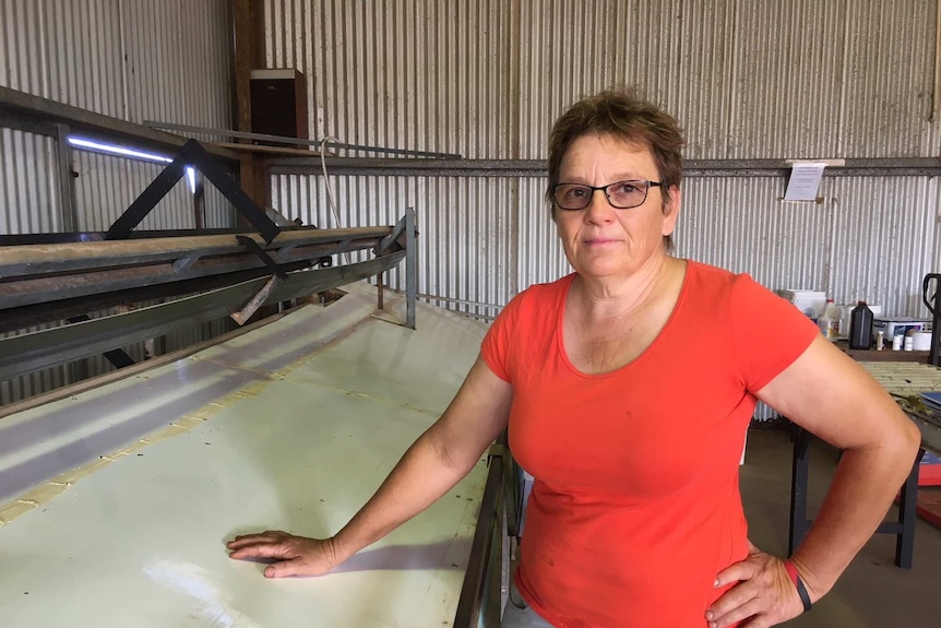 A woman stands next to an empty packing line