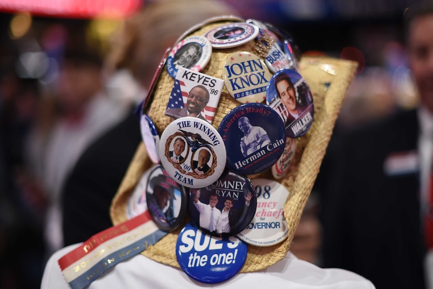 A Republican delegate sports a hat covered in badges.