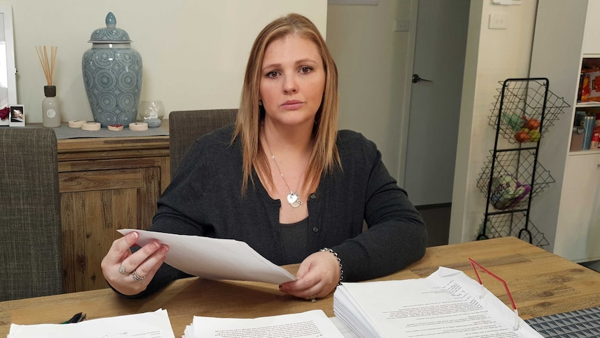 A woman holds sheets of paper.