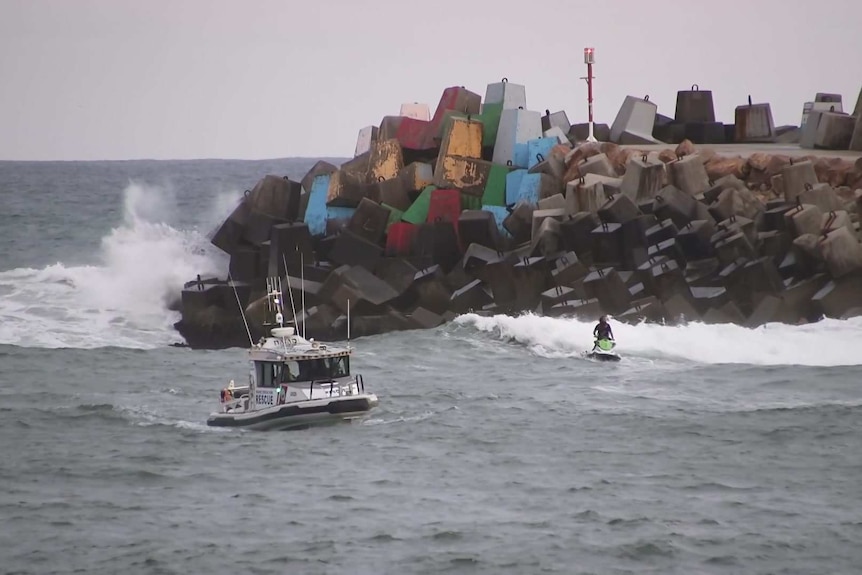 A police boat and jet ski rider conduct water search