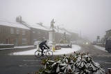 A cyclist rides through snowy conditions 
