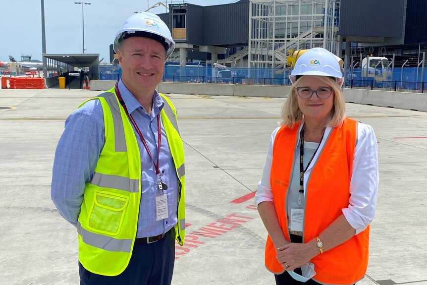 man and woman standing in high-vis jackets on the tarmac of Gold Coast airport