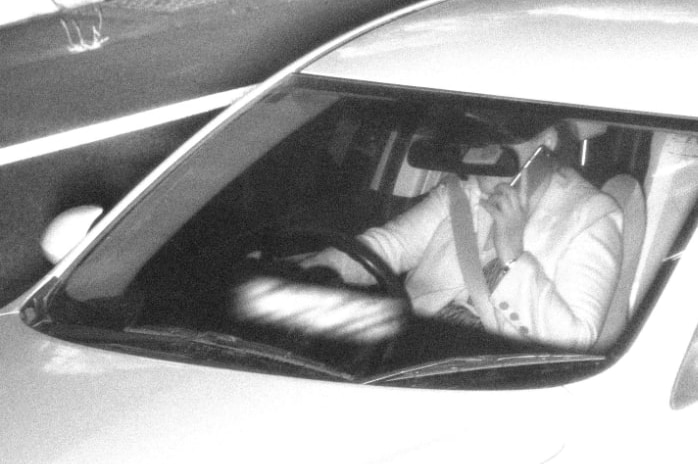 black and white photo of woman using phone while driving