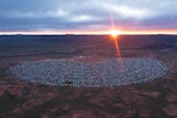 drone shot of large collection of caravans gathered around a stage on a big patch of land