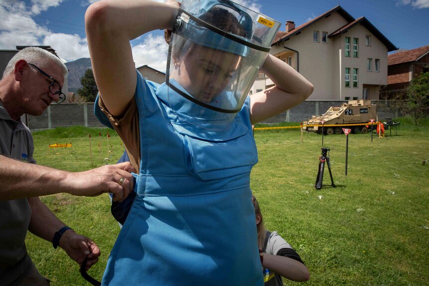 Anastasiia Minchukova puts on body armor and a visor during training.