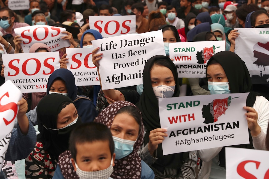 Afghan refugees living in Indonesia hold posters that read 'SOS' and 'Stand with Afghanistan' during a rally