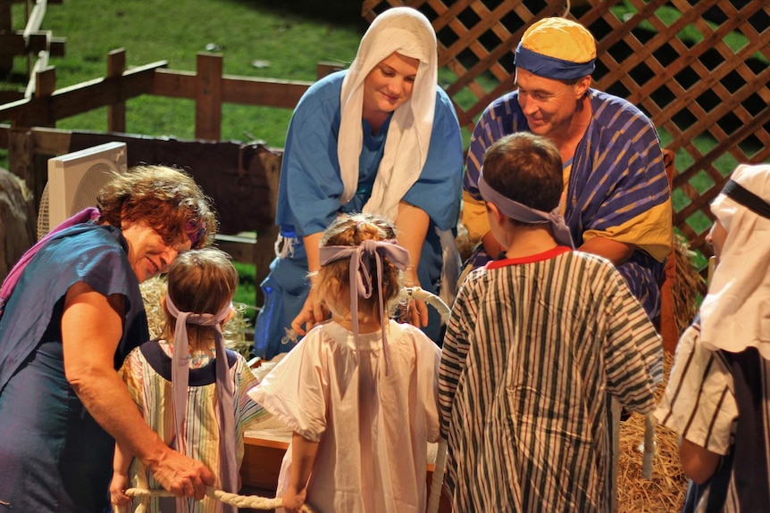 A nativity scene recreation - children dressed as shepherds look at a baby in a manger.