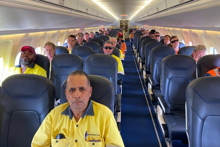 BHP mine workers sit socially distanced on a flight to the Newman mine in WA's Pilbara.