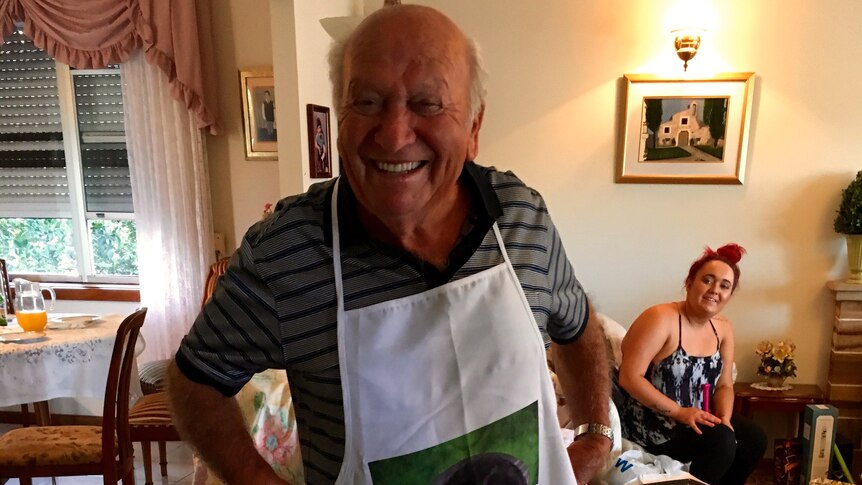 A man in a living room wearing a cooking apron