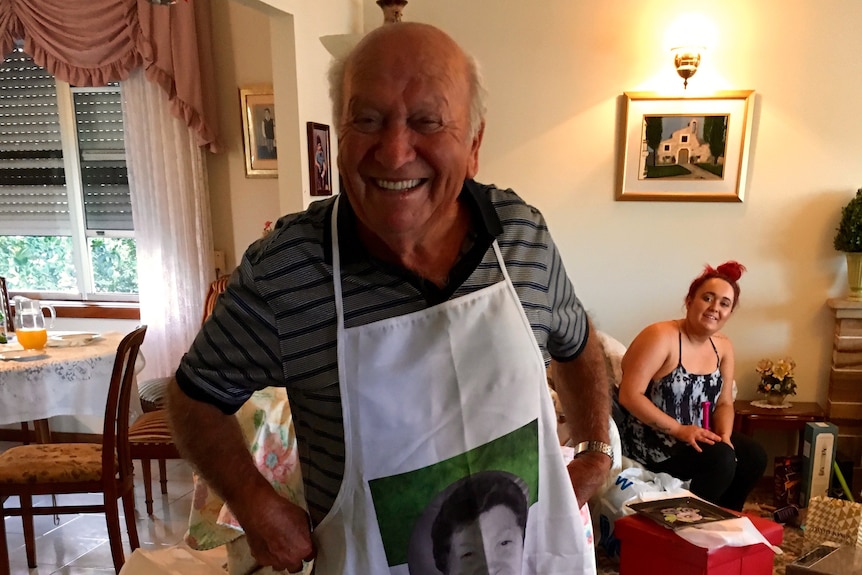 A man in a living room wearing a cooking apron