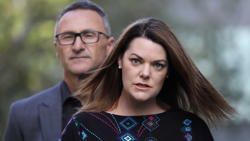 Hanson-Young looks angry. She's standing in front of Greens leader Richard Di Natale.
