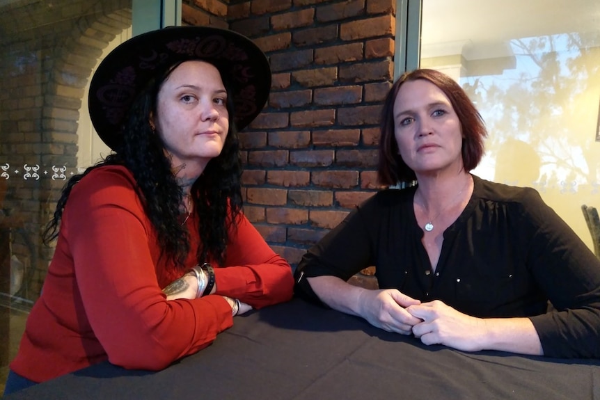 two women sit at a table looking at the camera